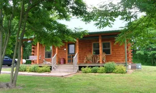 Eine Holzhütte hinter grünen Bäumen