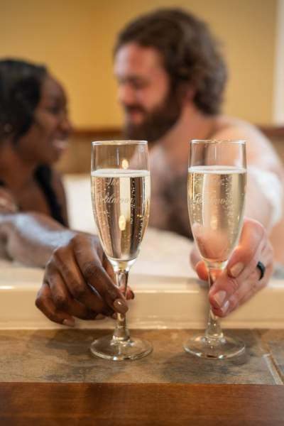 Ein Ehepaar trinkt Champagner in der Badewanne. 