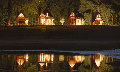 Vier nachts beleuchtete Kabinen, die sich im Wasser spiegeln