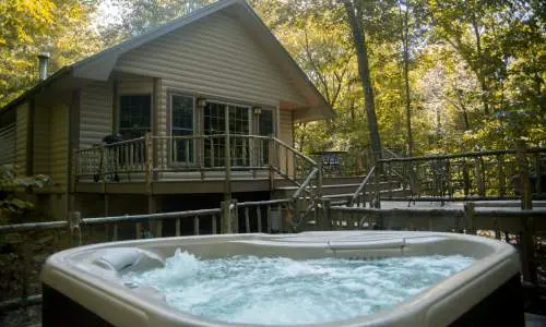 Ein sprudelnder Whirlpool vor einer Hütte inmitten von Bäumen