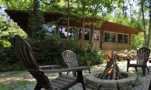 ein Haus mit Stühlen und Feuerstelle im Freien