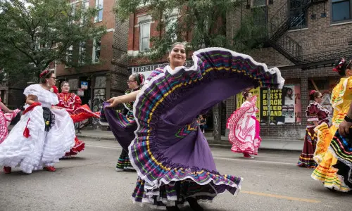 Folklórico-Tänzerinnen, die in traditionellen Trachten während einer Straßenparade in Chicago herumwirbeln.
