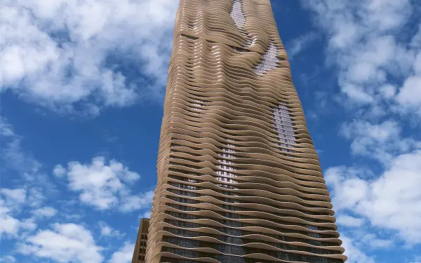 Das Äußere des Aqua Tower in Chicago vor einem wolkenverhangenen blauen Himmel.