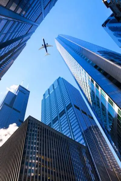 Blick in den Himmel mit den Wolkenkratzern von Chicago auf allen Seiten, ein Düsenflugzeug zieht über uns hinweg