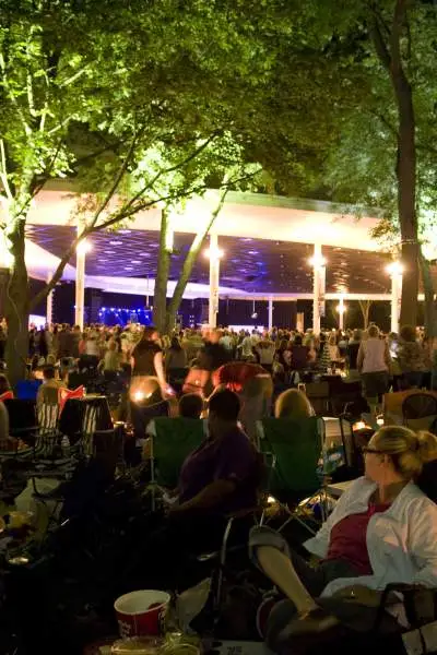 Festivalbesucher sitzen und stehen auf dem Rasen und genießen die Musik