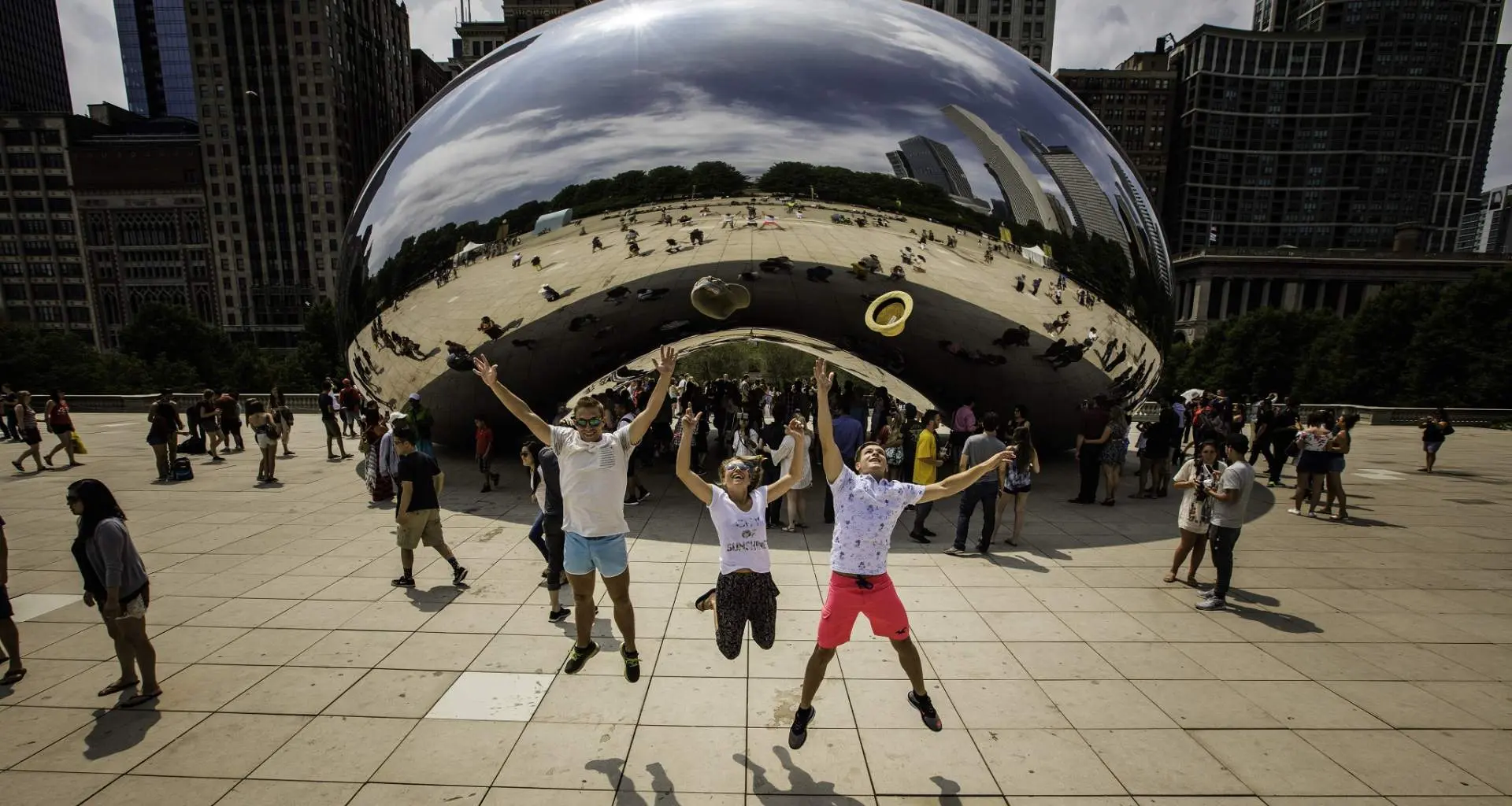 Drei Menschen, die vor dem Wahrzeichen The Bean in Chicago in die Luft springen