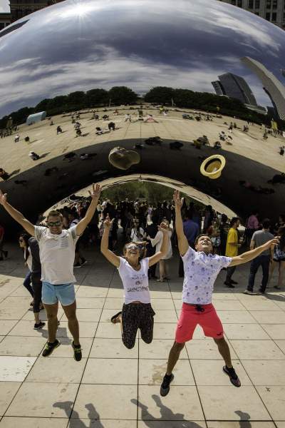Drei Menschen, die vor dem Wahrzeichen The Bean in Chicago in die Luft springen