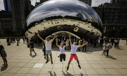 Drei Menschen, die vor dem Wahrzeichen The Bean in Chicago in die Luft springen
