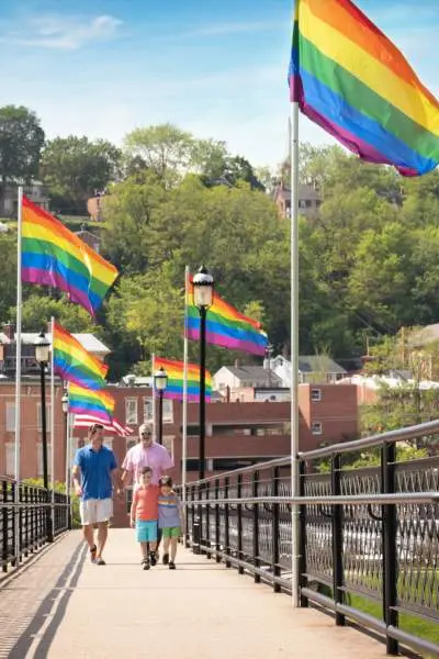 Menschen spazieren entlang einer Brücke in Galena, die mit Flaggen für Homosexuelle gesäumt ist