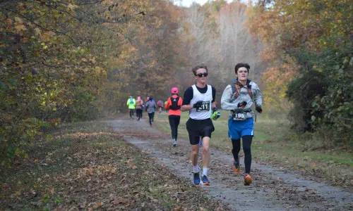 Läuferinnen und Läufer laufen im Herbst auf einer Outdoor-Strecke