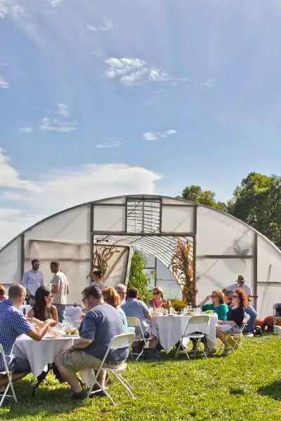 Gruppen von Menschen sitzen an Tischen draußen in der Sonne und genießen Essen und Trinken