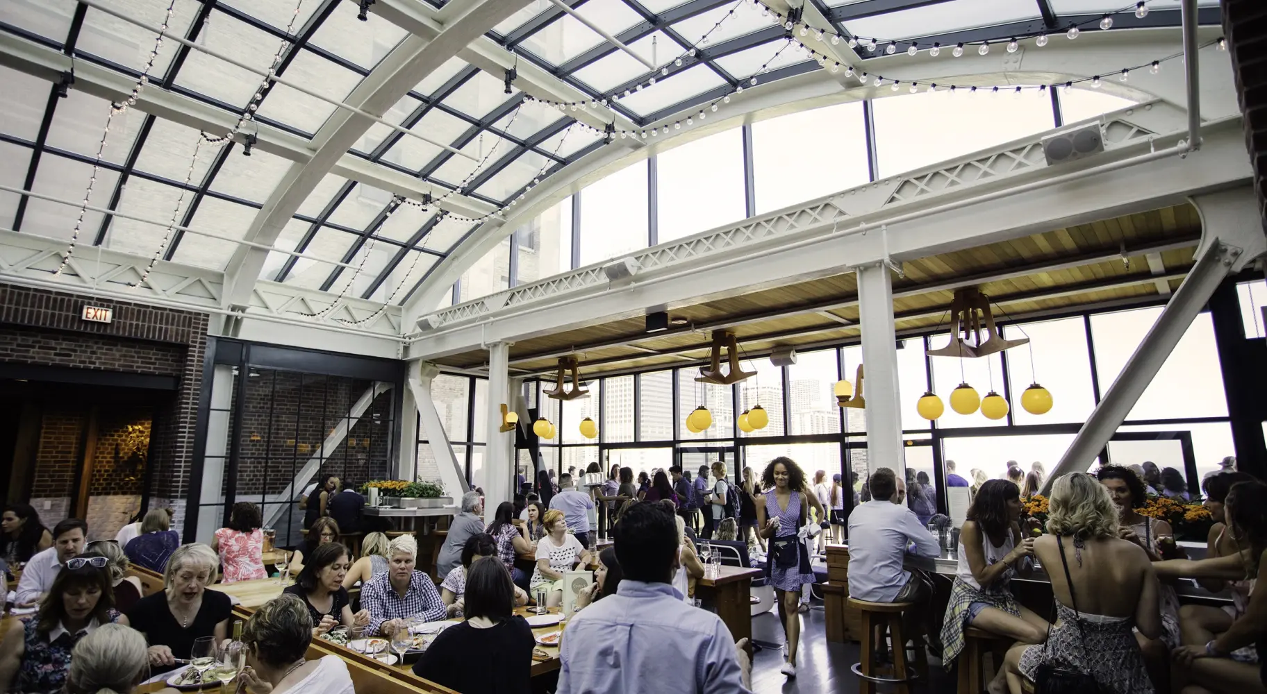 Eine Menschenmenge unter dem gläsernen Atrium von Cindy's Rooftop Bar