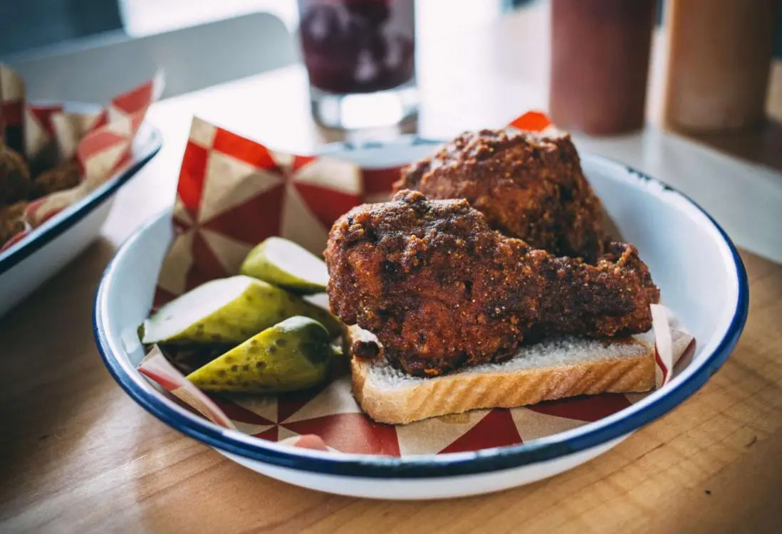 Zwei Hühnerkeulen und Essiggurken auf einem Stück Brot