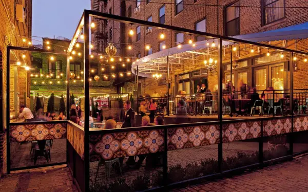 Gäste speisen auf der Außenterrasse unter Glühlampenlicht