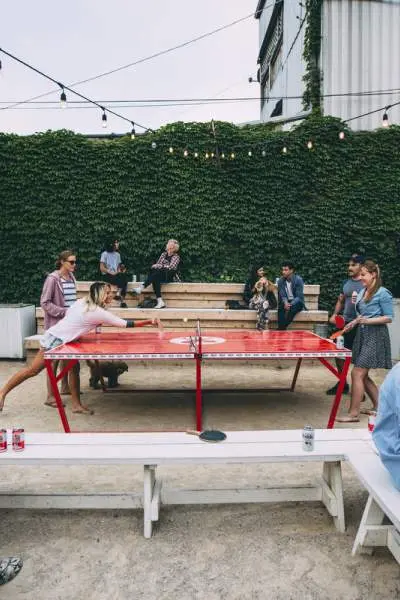 Die Gäste trinken Bier und spielen Tischtennis im Freien