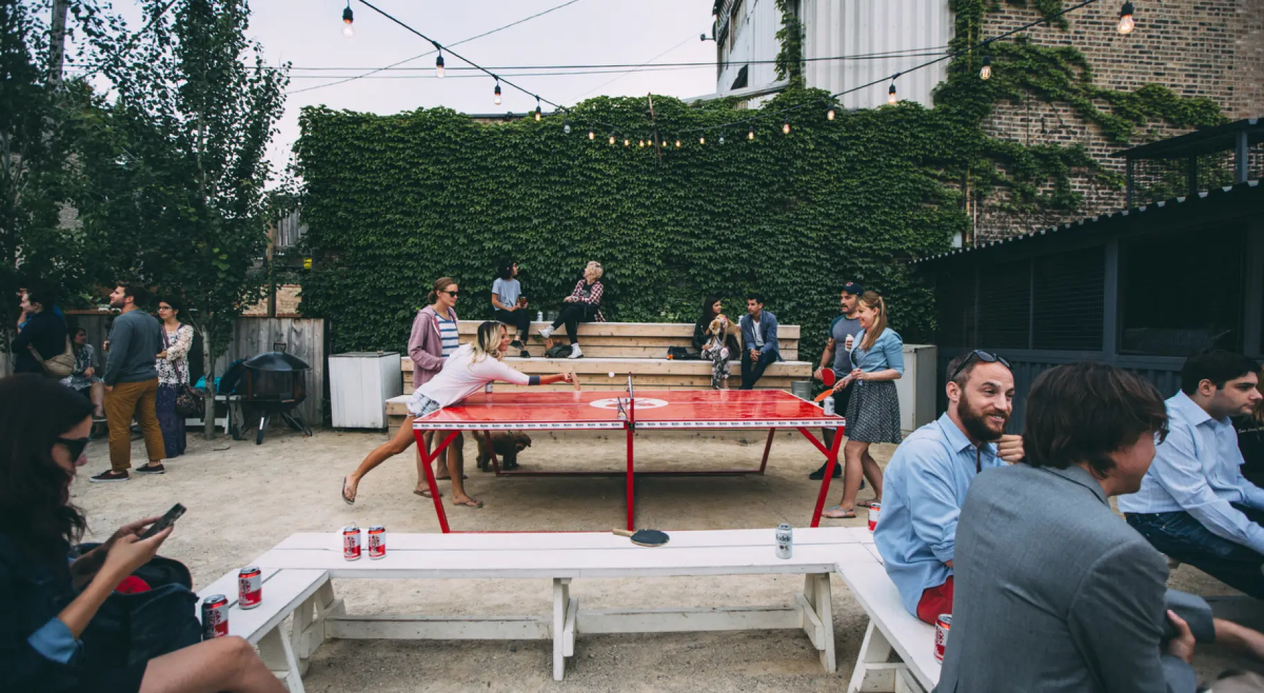 Die Gäste trinken Bier und spielen Tischtennis im Freien