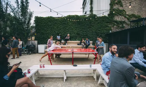 Die Gäste trinken Bier und spielen Tischtennis im Freien