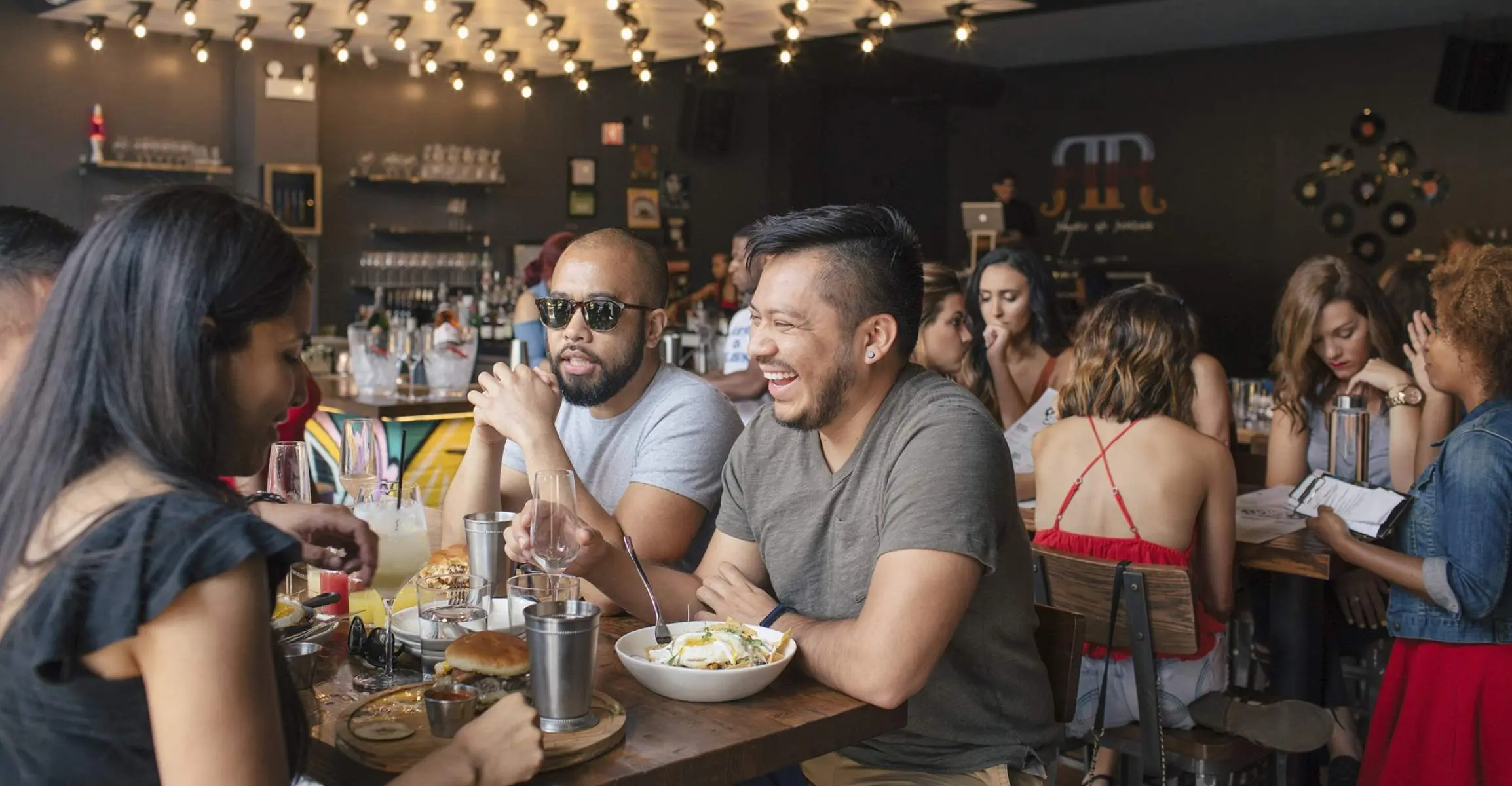 Drei Freunde beim Brunch in einer belebten Bar und einem Restaurant