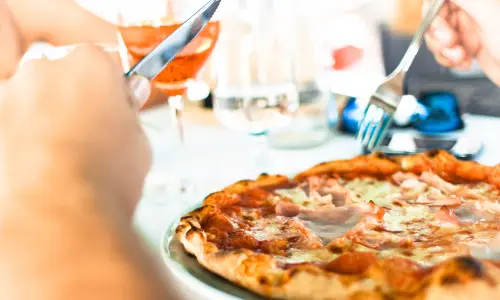 Person, die eine Pizza mit Messer und Gabel isst