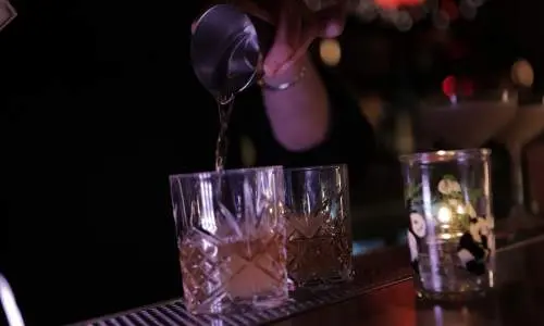 Ein Barkeeper schenkt Getränke in Gläser ein.