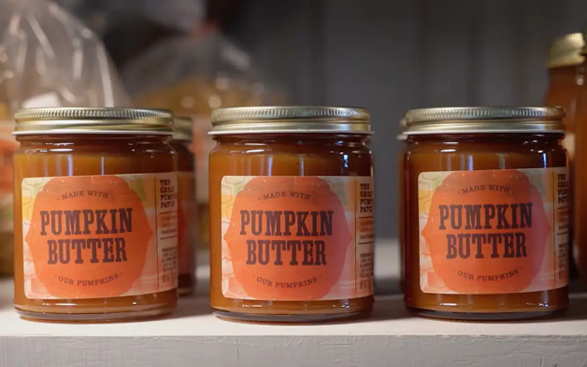 Drei Gläser mit der Aufschrift „Kürbisbutter“ standen in einer Reihe auf einem Regal. 