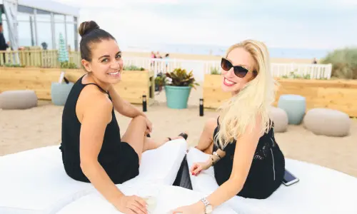 Zwei Frauen genießen einen Drink auf einer Strandliege