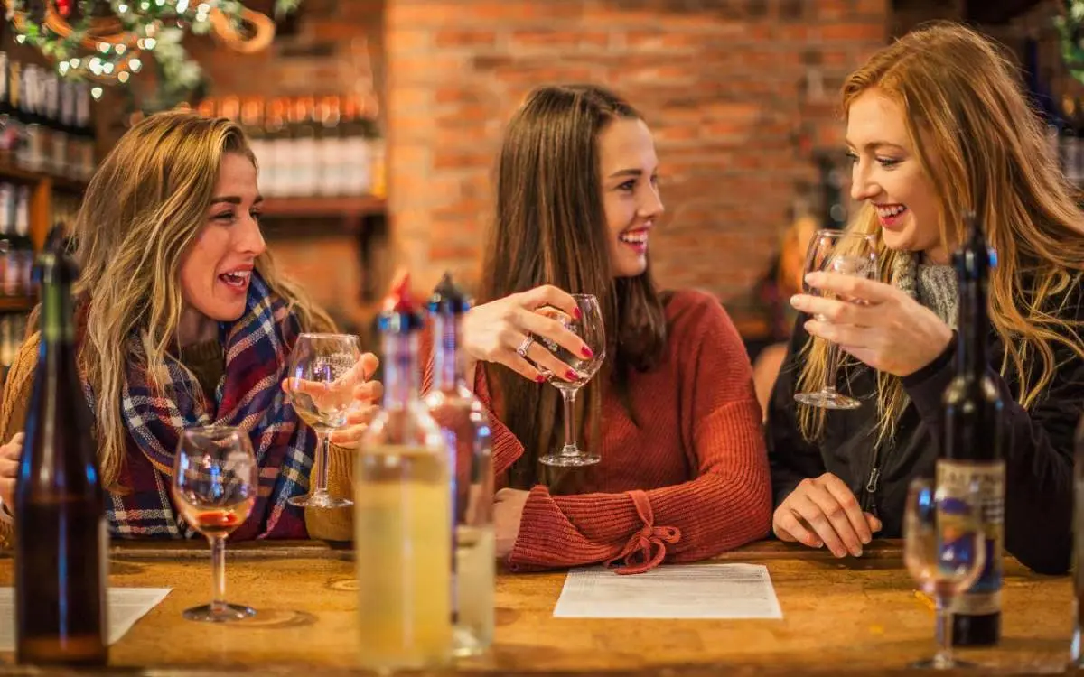 Drei Frauen sitzen an einem Tisch und genießen ein Glas Wein in einem Weinkeller