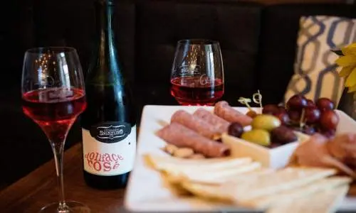 Eine Käseplatte und ein paar Gläser Wein stehen auf einem Tisch