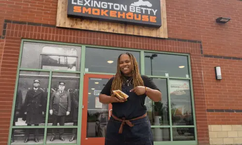 Eine Frau mit einem Hotdog in der Hand vor dem Lexington Betty Smokehouse.