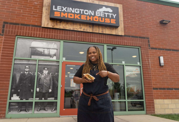 Eine Frau mit einem Hotdog in der Hand vor dem Lexington Betty Smokehouse.