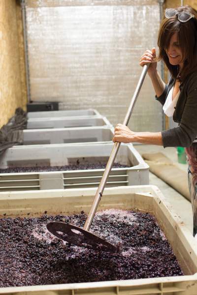 Eine Frau mischt die Trauben in einem großen Behälter, um Wein herzustellen.