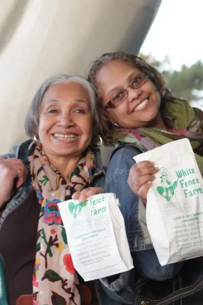 Zwei Frauen mit Tüten von White Fence Farm Brathähnchen