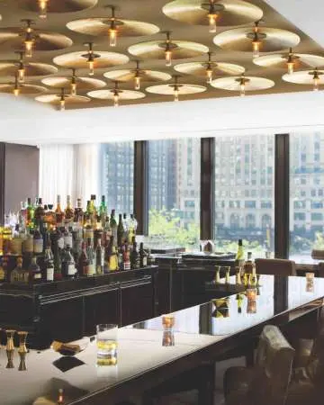 Das Innere einer Bar mit vielen Fenstern, die den Blick auf die Stadt freigeben.