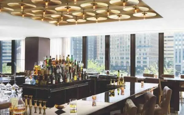 Das Innere einer Bar mit vielen Fenstern, die den Blick auf die Stadt freigeben.