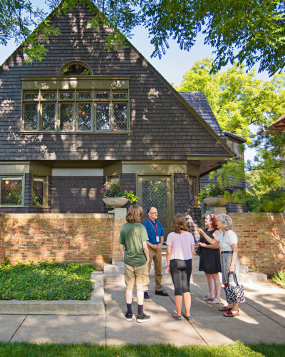 Ein Fremdenführer spricht zu einer Gruppe auf dem Bürgersteig vor Frank Lloyd Wrights Haus und Atelier in Oak Park