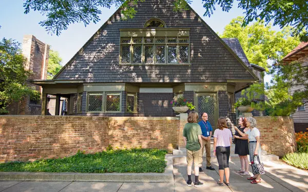 Ein Fremdenführer spricht zu einer Gruppe auf dem Bürgersteig vor Frank Lloyd Wrights Haus und Atelier in Oak Park