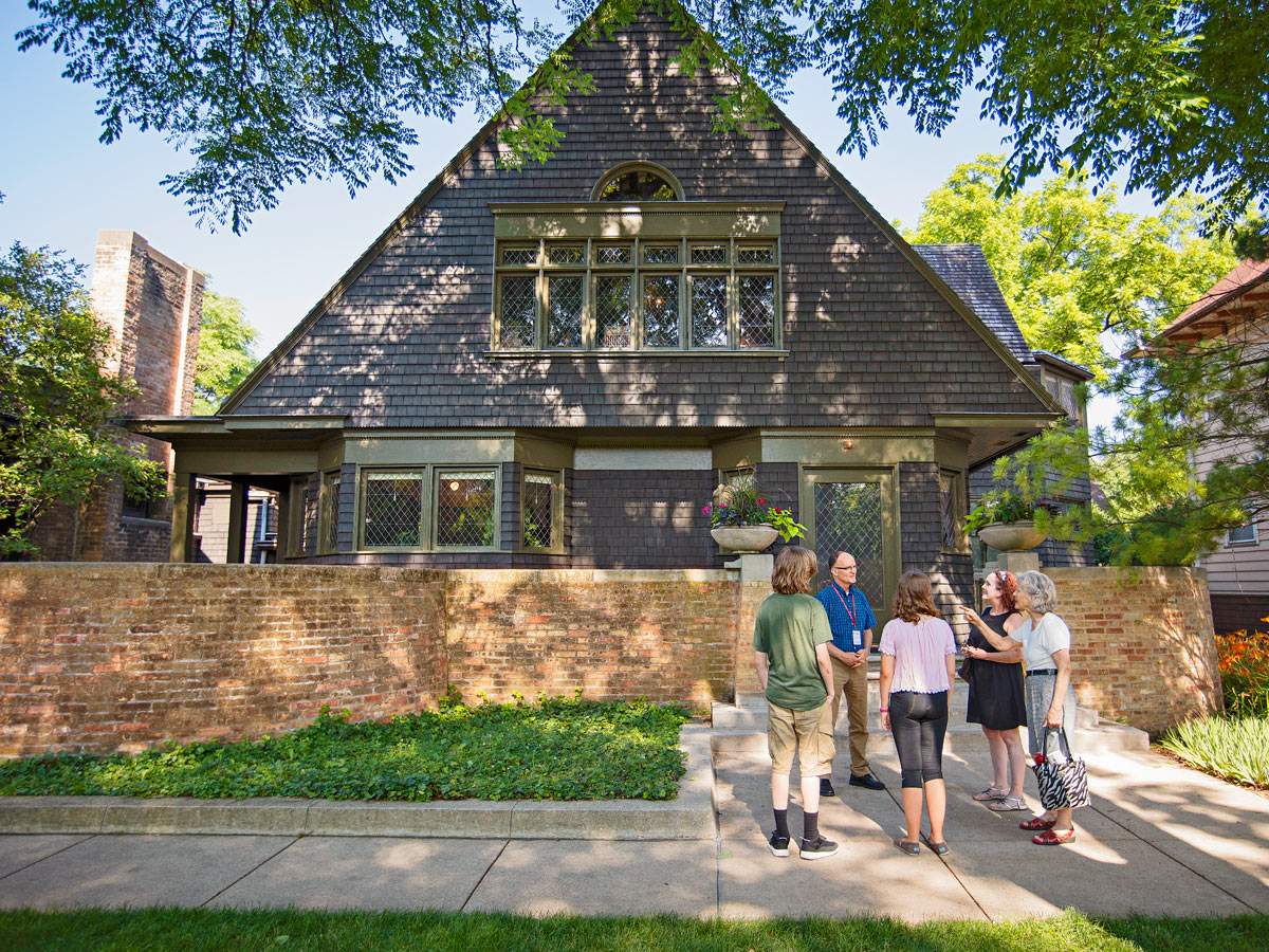 Ein Fremdenführer spricht zu einer Gruppe auf dem Bürgersteig vor Frank Lloyd Wrights Haus und Atelier in Oak Park
