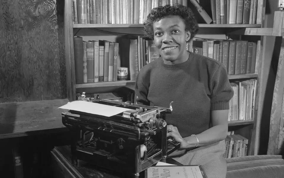 Frau sitzt an einer Schreibmaschine in einer Bibliothek