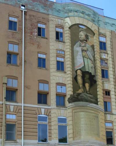 Ein großes, drei Stockwerke hohes Wandgemälde von Blackhawk an der Fassade eines Backsteingebäudes
