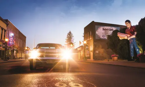 Ein Oldtimer mit eingeschalteten Scheinwerfern neben der riesigen Paul-Bunyon-Statue in Atlanta