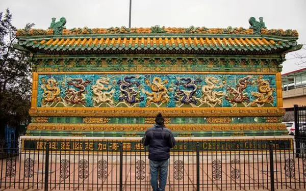 Eine Person steht vor der Neun-Drachen-Wand in Chinatown