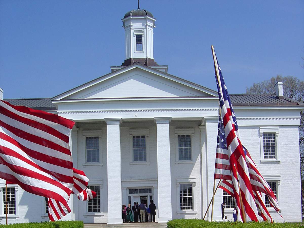 Ein großes weißes Haus mit amerikanischen Flaggen vor der Tür