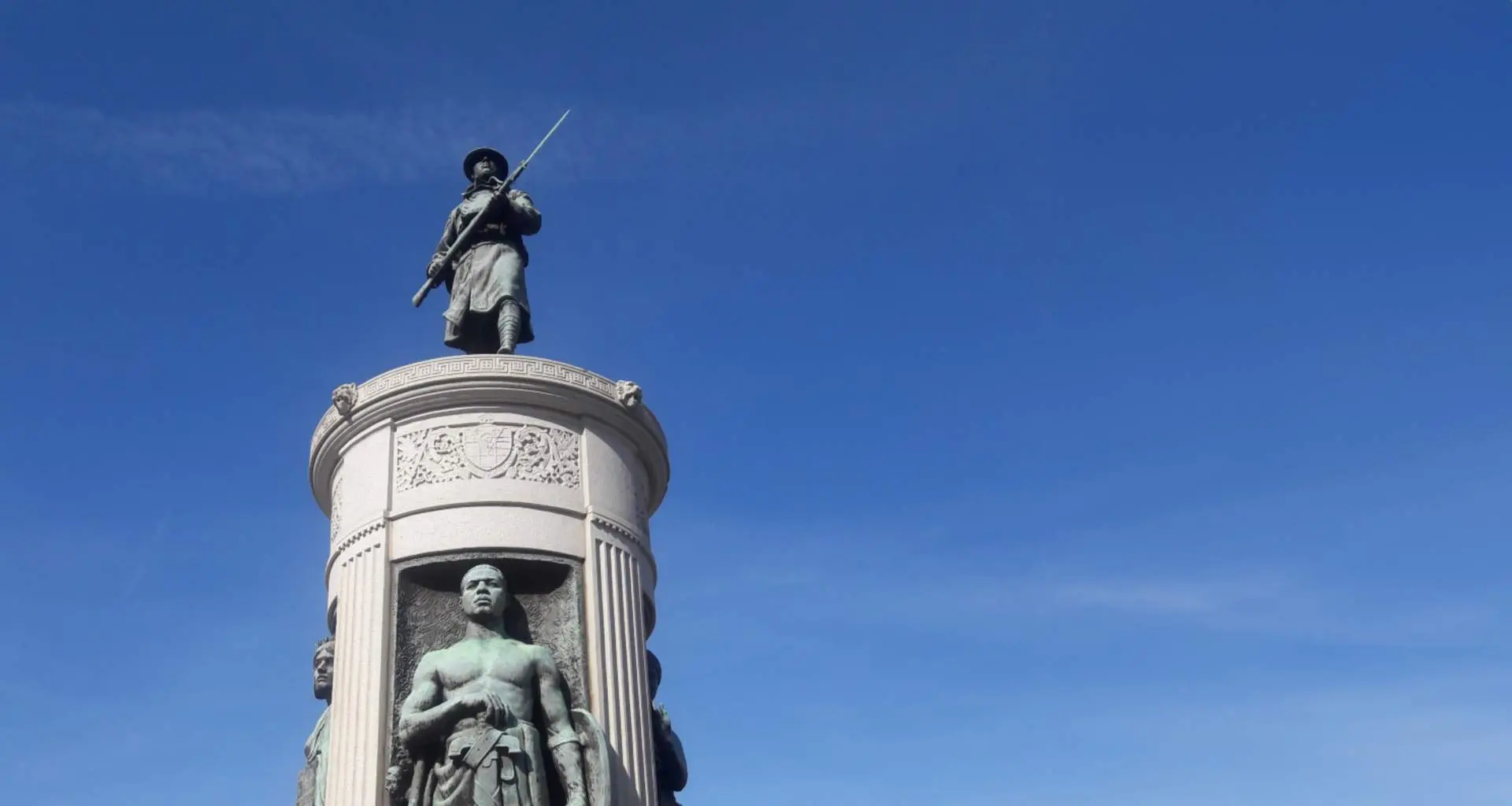 Eine verwitterte Bronzestatue eines Soldaten aus der Zeit des Ersten Weltkriegs auf einem Granitsockel