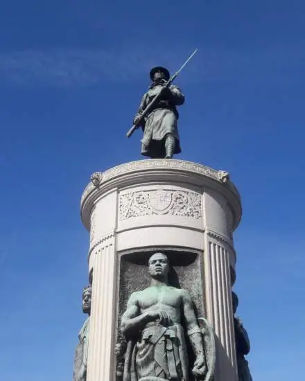 Eine verwitterte Bronzestatue eines Soldaten aus der Zeit des Ersten Weltkriegs auf einem Granitsockel