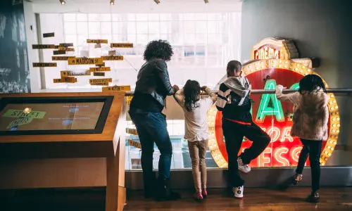 Kinder und Erwachsene schauen von einem Geländer herunter 