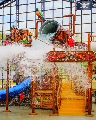 Ein Kippeimer spritzt Wasser über einen Piratenturm in einem Indoor-Wasserpark
