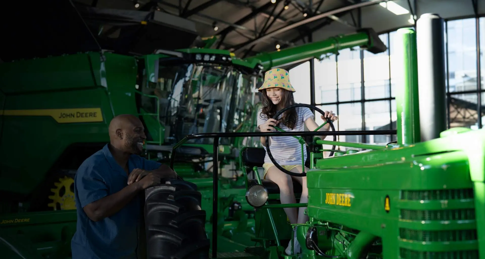 Ein Mädchen sitzt auf einem Traktor im John Deere Pavilion 