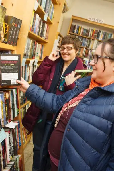 Frauen in einer Buchhandlung betrachten ein Regal mit Büchern
