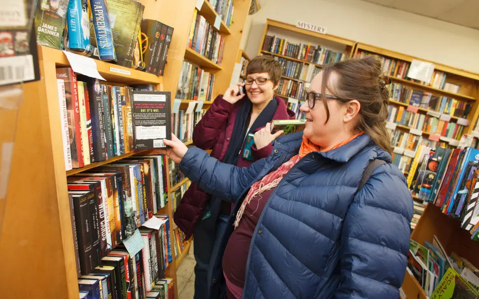 Frauen in einer Buchhandlung betrachten ein Regal mit Büchern