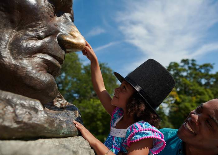 Ein Vater hebt seine Tochter hoch, um die Nase der Lincoln-Statue zu berühren.